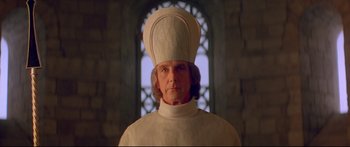 Movie still from “Ladyhawke” (1985), directed by Richard Donner – A man wearing a white hat in front of a stained glass window; Close Up shot, Low angle