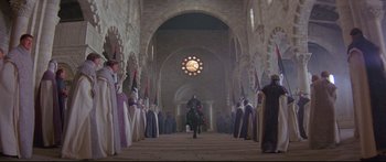 Movie still from “Ladyhawke” (1985), directed by Richard Donner – A man riding a horse in a church with people in the background; Extreme Wide shot, High angle