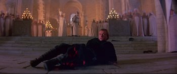 Movie still from “Ladyhawke” (1985), directed by Richard Donner – A man laying on the ground in front of a group of people; Wide shot, High angle