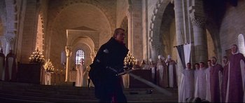 Movie still from “Ladyhawke” (1985), directed by Richard Donner – A man holding a sword in front of a group of people; Wide shot, Low angle