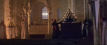 Movie still from “Ladyhawke” (1985), directed by Richard Donner – A woman standing in front of a large candle holder; Wide shot, Low angle