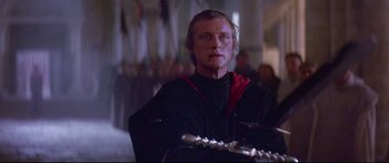 Movie still from “Ladyhawke” (1985), directed by Richard Donner – A man in black shirt and red shirt holding a flute; Close Up shot, Low angle