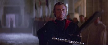 Movie still from “Ladyhawke” (1985), directed by Richard Donner – A man in a black shirt and a red and black shirt; Close Up shot, Low angle