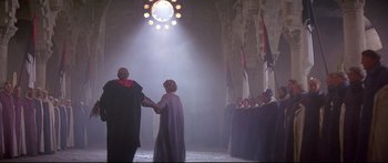 Movie still from “Ladyhawke” (1985), directed by Richard Donner – Two men in medieval garb holding hands in front of a group of people; Wide shot, High angle