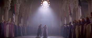 Movie still from “Ladyhawke” (1985), directed by Richard Donner – A couple of people that are holding hands in front of a building; Extreme Wide shot, Low angle