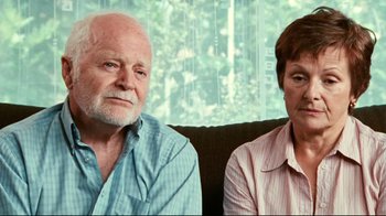 Movie still from “Lake Mungo” (2008), directed by Joel Anderson – An older man sitting next to an older woman on a couch; Close Up shot, High angle