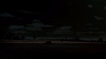 Movie still from “Lake Mungo” (2008), directed by Joel Anderson – A car is parked in a field under a dark night sky; Extreme Wide shot, Low angle