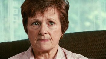 Movie still from “Lake Mungo” (2008), directed by Joel Anderson – An older woman sitting on a couch looking at the camera; Close Up shot, Low angle
