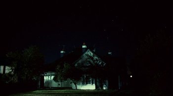 Movie still from “Lake Mungo” (2008), directed by Joel Anderson – A building with a tree in front of it at night time; Extreme Wide shot, Low angle