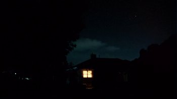 Movie still from “Lake Mungo” (2008), directed by Joel Anderson – A house is lit up at night in the dark; Extreme Wide shot, Low angle