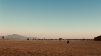 Movie still from “Lake Mungo” (2008), directed by Joel Anderson – A couple of people walking across a field; Extreme Wide shot, Low angle