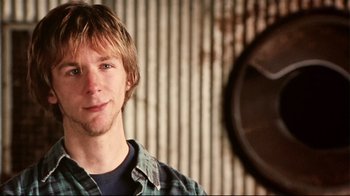 Movie still from “Lake Mungo” (2008), directed by Joel Anderson – A young man is smiling for the camera; Close Up shot, Low angle