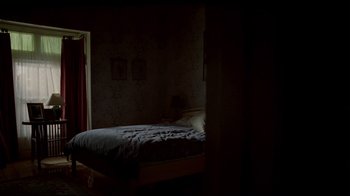 Movie still from “Lake Mungo” (2008), directed by Joel Anderson – A bed in a dark room lit by a lamp; Wide shot, High angle