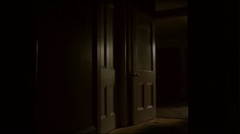 Movie still from “Lake Mungo” (2008), directed by Joel Anderson – A dimly - lit room with two doors open; Wide shot, Low angle