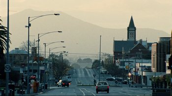 Movie still from “Lake Mungo” (2008), directed by Joel Anderson – Cars driving down a street in a city; Extreme Wide shot, Low angle