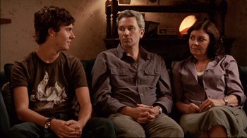 Movie still from “Lake Mungo” (2008), directed by Joel Anderson – A man and two women sitting next to each other on a couch; Medium shot, Over the shoulder angle