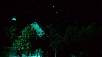 Movie still from “Lake Mungo” (2008), directed by Joel Anderson – A house is lit up at night under a starry sky; Extreme Wide shot, Low angle