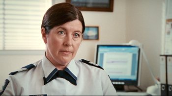 Movie still from “Lake Mungo” (2008), directed by Joel Anderson – A woman wearing a police uniform in front of a computer; Close Up shot, Over the shoulder angle