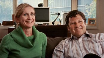 Movie still from “Lake Mungo” (2008), directed by Joel Anderson – A man and a woman sitting next to each other on a couch; Medium shot, Over the shoulder angle
