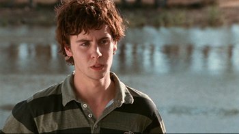 Movie still from “Lake Mungo” (2008), directed by Joel Anderson – A young man in a striped shirt is looking at the camera; Close Up shot, Low angle