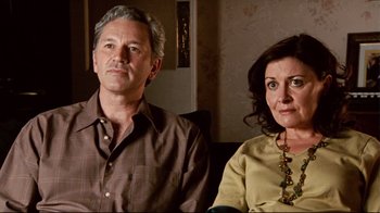 Movie still from “Lake Mungo” (2008), directed by Joel Anderson – A man and a woman sitting next to each other on a couch; Close Up shot, High angle