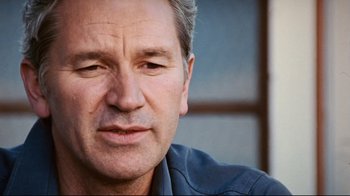 Movie still from “Lake Mungo” (2008), directed by Joel Anderson – A man's face with a blue shirt on; Close Up shot, Low angle