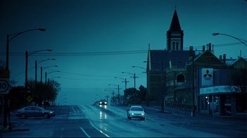 Movie still from “Lake Mungo” (2008), directed by Joel Anderson – Cars driving down a street at night in the rain; Extreme Wide shot, Low angle
