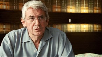 Movie still from “Lake Mungo” (2008), directed by Joel Anderson – An older man with white hair wearing glasses and a blue shirt; Close Up shot, Over the shoulder angle