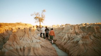 Movie still from “Lake Mungo” (2008), directed by Joel Anderson – A group of people walking on a trail in the desert; Extreme Wide shot, High angle