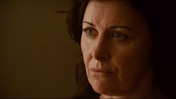 Movie still from “Lake Mungo” (2008), directed by Joel Anderson – A woman's face in a dark room; Close Up shot, Over the shoulder angle