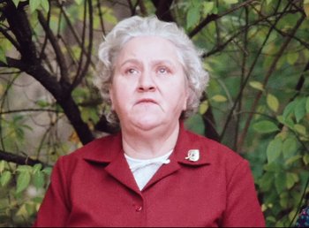 Movie still from “Land of Silence and Darkness” (1971), directed by Werner Herzog – An older woman wearing a red jacket and a white shirt; Close Up shot, Low angle