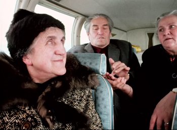 Movie still from “Land of Silence and Darkness” (1971), directed by Werner Herzog – An older woman sitting next to an older man on a bus; Medium shot, Low angle