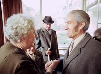 Movie still from “Land of Silence and Darkness” (1971), directed by Werner Herzog – An older man and a younger man in a suit and tie; Medium shot, Over the shoulder angle