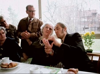 Movie still from “Land of Silence and Darkness” (1971), directed by Werner Herzog – Two men and a woman sitting at a dining table; Medium shot, Over the shoulder angle