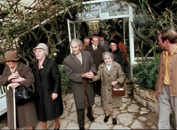 Movie still from “Land of Silence and Darkness” (1971), directed by Werner Herzog – A group of older people walking down a walkway; Wide shot, High angle