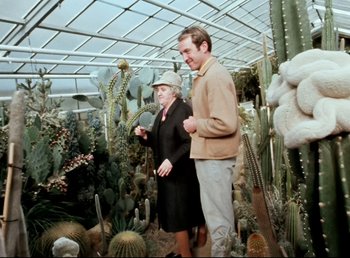 Movie still from “Land of Silence and Darkness” (1971), directed by Werner Herzog – A man and a woman standing in front of cacti and succulents; Wide shot, Over the shoulder angle