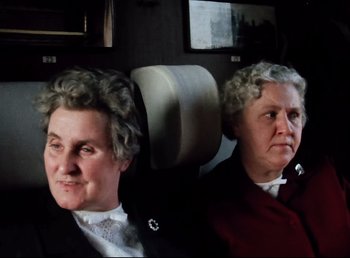 Movie still from “Land of Silence and Darkness” (1971), directed by Werner Herzog – Two older women sitting in a car looking at the camera; Medium shot, High angle