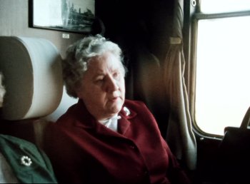 Movie still from “Land of Silence and Darkness” (1971), directed by Werner Herzog – An older woman sitting on a train looking out the window; Medium shot, High angle