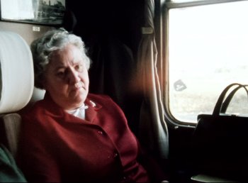 Movie still from “Land of Silence and Darkness” (1971), directed by Werner Herzog – An older woman sitting on a train looking out the window; Medium shot, High angle