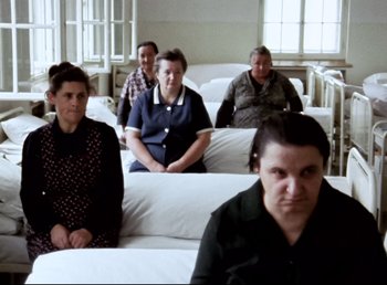 Movie still from “Land of Silence and Darkness” (1971), directed by Werner Herzog – A group of people sitting in a room; Wide shot, High angle