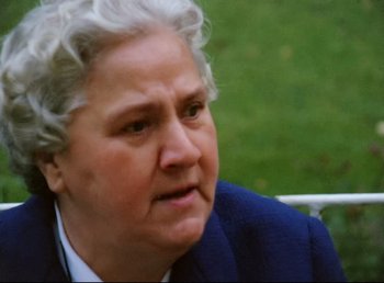 Movie still from “Land of Silence and Darkness” (1971), directed by Werner Herzog – An older woman in a blue suit is sitting outside; Close Up shot, Over the shoulder angle