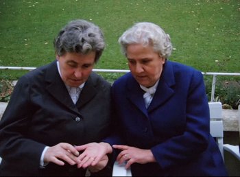 Movie still from “Land of Silence and Darkness” (1971), directed by Werner Herzog – Two older women sitting next to each other on a park bench; Medium shot, High angle