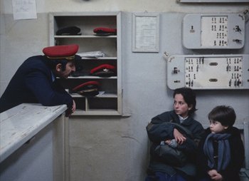 Movie still from “Landscape in the Mist” (1988), directed by Theodoros Angelopoulos – Two women and a boy sitting in a room; Medium shot, High angle