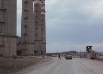 Movie still from “Landscape in the Mist” (1988), directed by Theodoros Angelopoulos – A person walking down a street near a tall building; Extreme Wide shot, Low angle