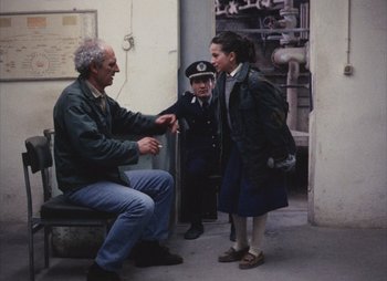 Movie still from “Landscape in the Mist” (1988), directed by Theodoros Angelopoulos – A man and two young girls talking to each other; Medium shot, Over the shoulder angle