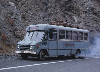 Movie still from “Landscape in the Mist” (1988), directed by Theodoros Angelopoulos – An old bus is driving down the street; Extreme Wide shot, High angle