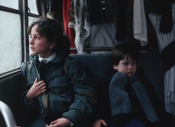Movie still from “Landscape in the Mist” (1988), directed by Theodoros Angelopoulos – Two young boys sitting on a bus together; Medium shot, Low angle