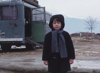 Movie still from “Landscape in the Mist” (1988), directed by Theodoros Angelopoulos – A little girl standing in front of an old bus; Wide shot, Low angle
