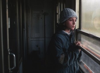 Movie still from “Landscape in the Mist” (1988), directed by Theodoros Angelopoulos – A woman standing in front of a train window; Close Up shot, High angle