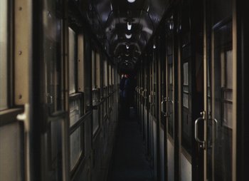 Movie still from “Landscape in the Mist” (1988), directed by Theodoros Angelopoulos – A person walking down a hallway in a train car; Wide shot, High angle